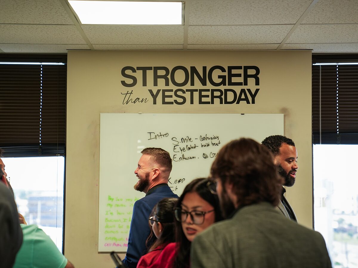 Coast to Coast Events team members meeting in the office beneath a "Stronger than Yesterday" wall sign